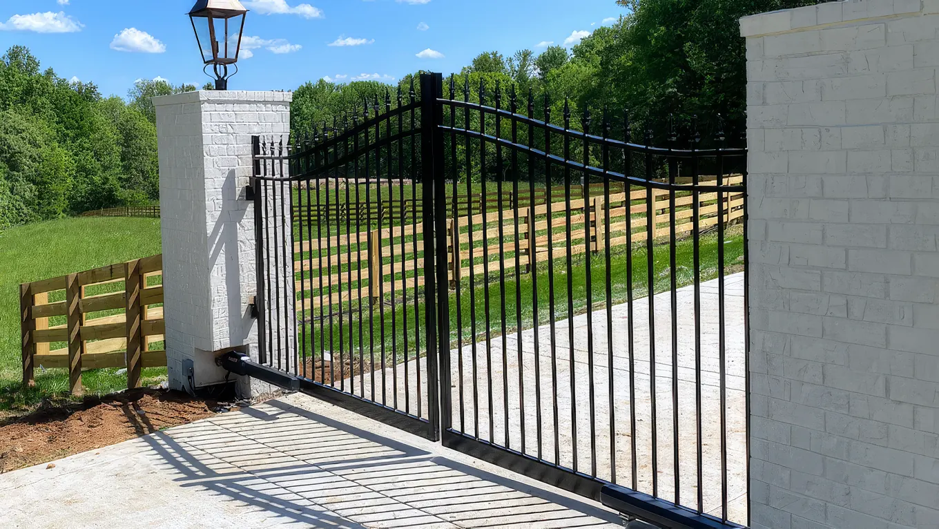 Arched iron gate with spear finials set between white brick columns topped with gas lanterns