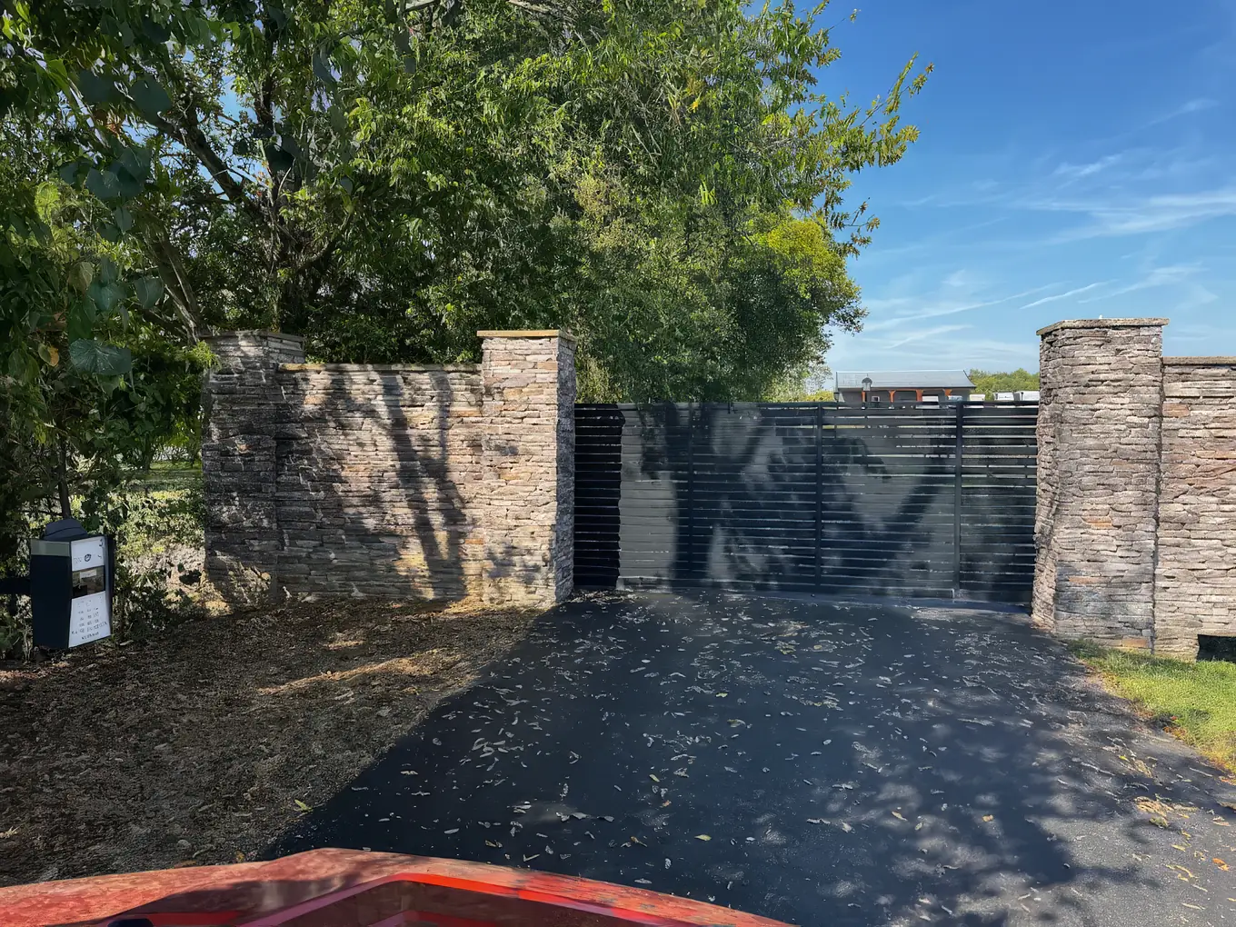 Modern horizontal slat gate set between tall stacked stone masonry walls